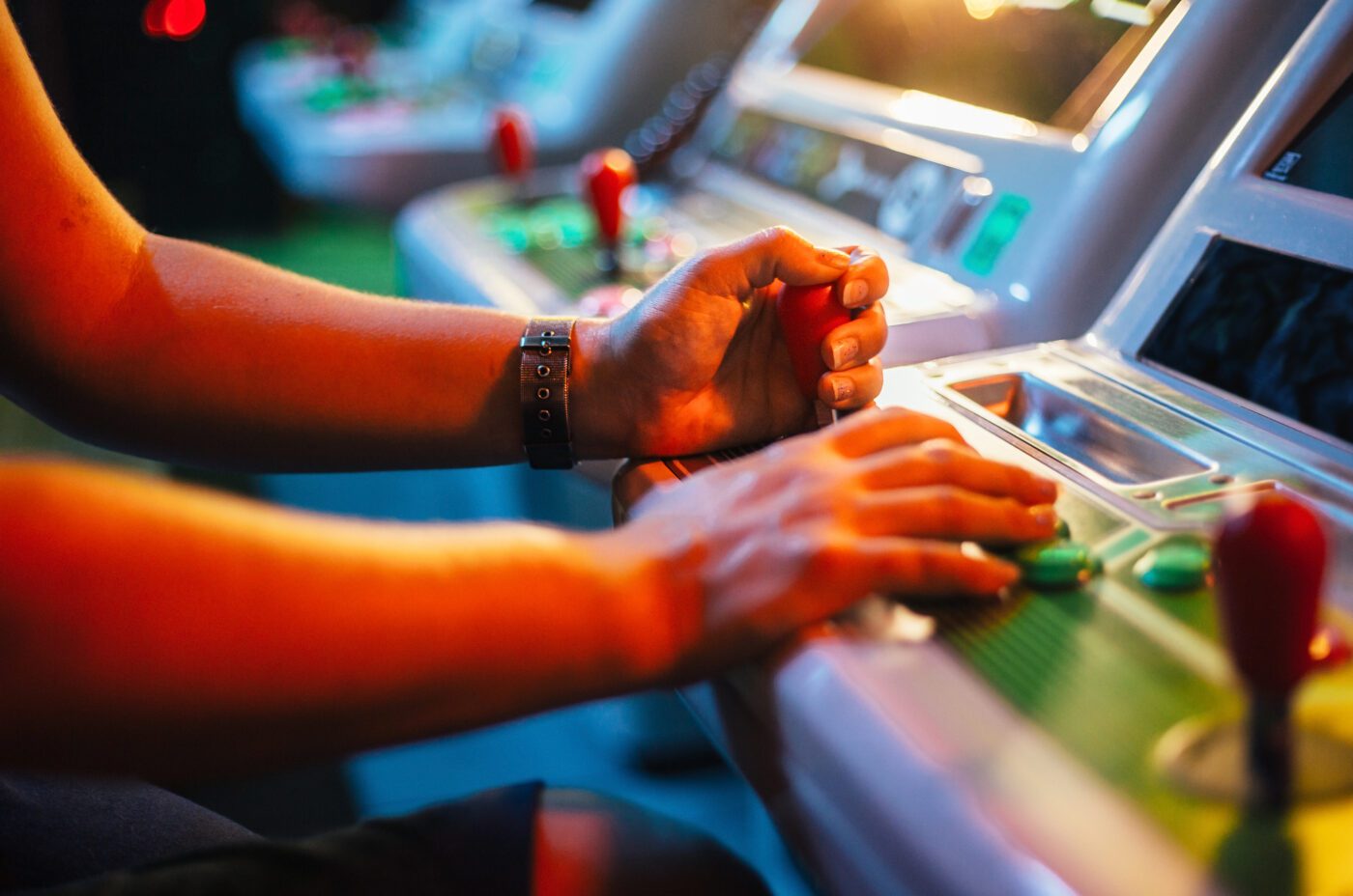 Detail on hands playing with joystick on old vintage arcade game in a dark room for playing video games t Game On! Exhibition at the National Museum of Scotland.