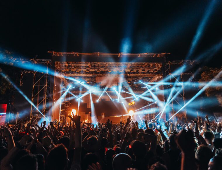 Silhouettes of concert crowd in front of bright stage lights on Terminal V Halloween music festival