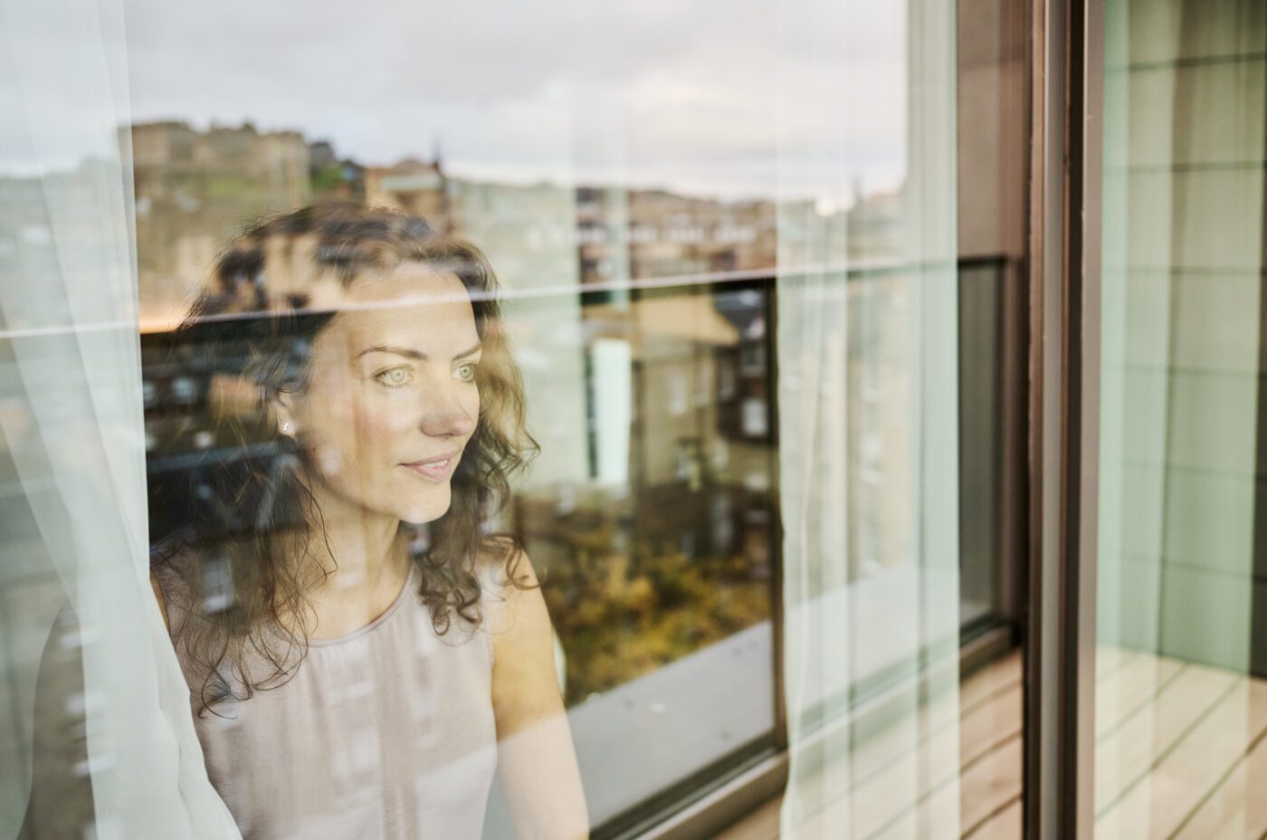 A guest looking out admiring the view from her Junior Suite room at The Resident Edinburgh, watching Edinburgh Castle, Princes Street Gardens, the West End and The Georgian New Town