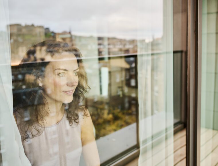 A guest looking out admiring the view from her Junior Suite room at The Resident Edinburgh, watching Edinburgh Castle, Princes Street Gardens, the West End and The Georgian New Town